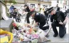  ?? MARTIN RICKETT — THE ASSOCIATED PRESS ?? Police officers add to the flowers for the victims of Monday night’s pop concert explosion, in St. Ann’s Square, Manchester.
