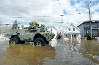  ?? SEAN KILPATRICK/THE CANADIAN PRESS ?? The military drives along a flooded street as waters breach the Gatineau River and flood the neighbourh­ood in Gatineau, Quebe., on Wednesday.