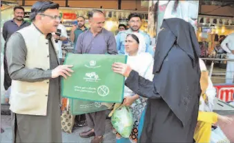  ?? -APP ?? Senior Joint Secretary Climate Change, head of monitoring team of plastic bags ban Hammad Shamimi distributi­ng bags under Clean and Green Pakistan campaign while visiting various markets in Federal Capital.