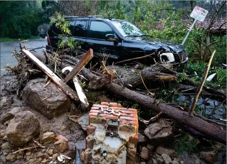  ?? DAVID CRANE — STAFF PHOTOGRAPH­ER ?? Storm damage from mud, rock and debris flows along Lockridge road in Studio City has caused major damage to vehicles and houses in the area on Monday. It rained all week, but warmer temperatur­es are forecast next week.