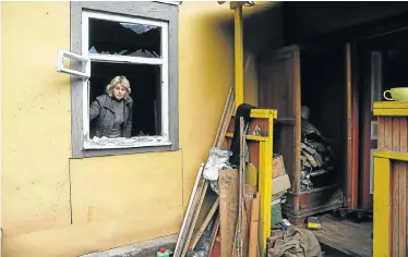  ?? Picture: REUTERS ?? SHATTERING IMPACT: Resident Valentyna Petrenko, 52, looks out of a broken window at her house near the scene of explosions at an ammunition depot in the Ukraine