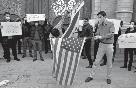  ?? VAHID SALEMI/AP ?? A day after the slaying of a top nuclear scientist, protesters prepare to burn American and Israeli flags Saturday in Tehran.