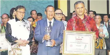  ??  ?? Abdul Rashid (centre) and Mohd Nizam (right) pose for photo with Abang Johari (left) after receiving the award.