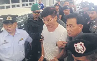  ?? assaWin pinitWong ?? Police escort former doctor Supat Laohawatta­na after he was extradited from Myanmar yesterday. He fled there to escape the death sentence.