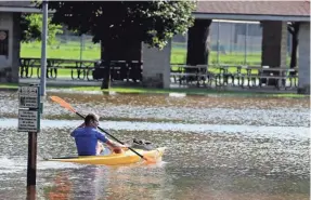  ?? RICK WOOD / MILWAUKEE JOURNAL SENTINEL ?? A man in a kayak checks out the flooding Tuesday on the river at Village Park in Thiensvill­e.