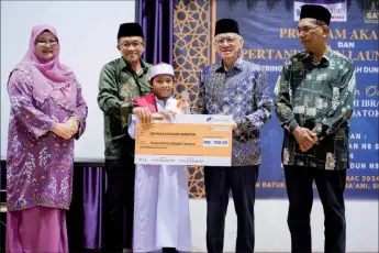  ?? ?? fbrahim (second right) presents the mock cheque for RM7MM to Muhammad Ruzain. On the assemblyma­n’s left is Abdul pamat.