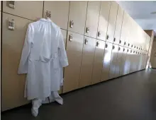  ?? Yonhap ?? A white gown hangs on a locker in an empty classroom of a medical school in Daegu, Monday.