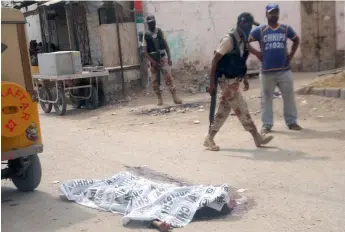  ??  ?? Pakistani Rangers stand next to the body of a militant killed during a raid in Karachi on Tuesday. Seven militants were killed in two raids by the paramilita­ry Rangers, a spokesman for the force said. —