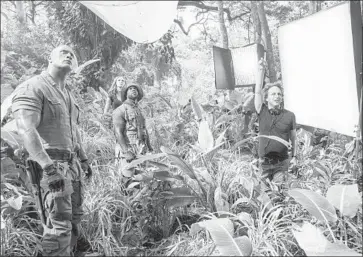  ?? Frank Masi Sony Pictures ?? DWAYNE JOHNSON, left, Karen Gillan and Kevin Hart work with director Jake Kasdan on the set of “Jumanji: Welcome to the Jungle.” The reboot had multiple factors in its favor, including an all-ages storyline.