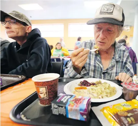  ?? NICK BRANCACCIO ?? Stuart Klingler, right, enjoys a turkey dinner with hundreds of others at the Salvation Army on Sunday. Thanks to a donation from a local businessma­n, the Salvation Army held its first Thanksgivi­ng dinner.