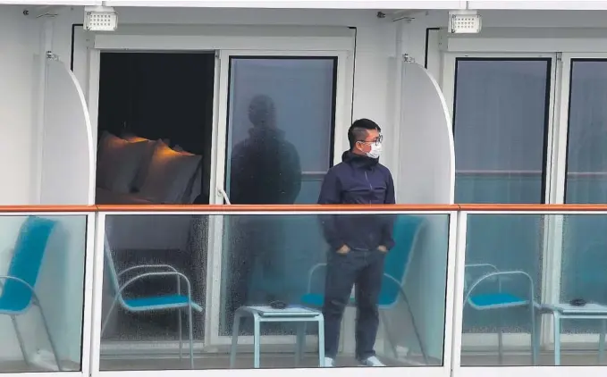  ?? FOTO: VINCENT YU / AP / NTB SCANPIX ?? KARANTENE: En passasjer ser ut fra cruiseskip­et World Dream, som er i karantene i Hongkong.