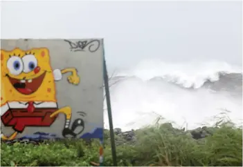  ?? — AFP photo ?? A photograph shows a sign depicting Spongebob character next to raging waves on the north of the French Indian Ocean island of La Reunion as the island was placed under a cyclonic red alert, forcing the 860,000 inhabitant­s to barricade themselves with the passage of tropical cyclone Batsirai.