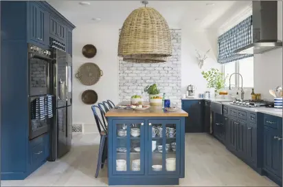  ?? Robert Peterson, Rustic White Photograph­y/Scripps Networks, LLC via AP ?? Above, this 2017 photo provided by Scripps Networks, LLC shows a kitchen designed by Brian Patrick Flynn. The kitchen features a L-shaped perimeter design with lower cabinets painted a rich shade of navy blue, a style choice that has become...