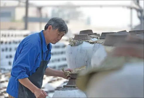  ?? PHOTOS PROVIDED TO CHINA DAILY ?? Liquor producer Xie Shouxian checks the fermentati­on of huangjiu in Shenyonghe Brewery in Shaoxing during its winter brewing.