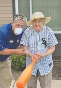  ?? ?? Andy Taranto, the Environmen­tal Services director at Harvester Place, assists a resident at bat during a friendly baseball game.