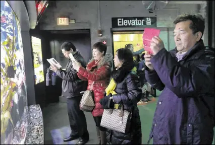  ?? ELISE AMENDOLA / AP ?? Tourists from China take pictures at the New England Aquarium in Boston. In cities across the country, the American hospitalit­y industry is stepping up efforts to make Chinese visitors feel more welcome, training staff in Chinese etiquette and...