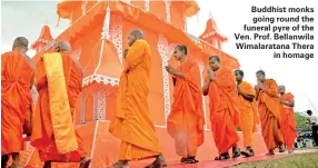  ??  ?? Buddhist monks going round the funeral pyre of the Ven. Prof. Bellanwila Wimalarata­na Thera in homage