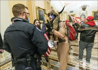  ?? AP PHOTO/MANUEL BALCE CENETA ?? In this Jan. 6 file photo supporters of President Donald Trump are confronted by U.S. Capitol Police officers outside the Senate Chamber inside the Capitol in Washington. An Arizona man seen in photos and video of the mob wearing a fur hat with horns was also charged Saturday in Wednesday’s chaos. Jacob Anthony Chansley, who also goes by the name Jake Angeli, was taken into custody Saturday.