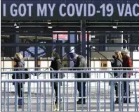  ?? Photo by Steven Senne/Associated Press ?? People wait in a socially distanced line last month to get their COVID-19 vaccinatio­ns at Gillette Stadium in Foxboro.
