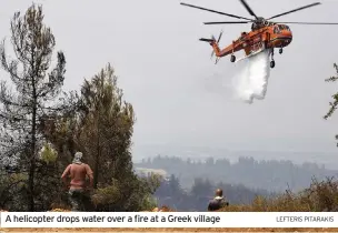  ?? LEFTERIS PITARAKIS ?? A helicopter drops water over a fire at a Greek village