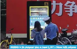  ?? — AFP ?? SHANGHAI: In this photograph taken on August 9, 2017 a Chinese traffic policeman explains to a girl about the installed facial recognitio­n screen at a road intersecti­on in Shanghai.