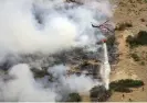  ?? Utah. Photograph: Kristin Murphy/AP ?? Firefighte­rs battle a wildfire from the ground as a helicopter drops water above them in Springvill­e,