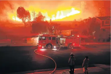  ?? Picture: KEVORK DJANSEZIAN/GETTY IMAGES/AFP ?? RUNNING WILD: A Los Angeles County firefighte­r looks on as the out-of-control ‘Woolsey Fire’ explodes behind a house in the West Hills neighbourh­ood in Los Angeles