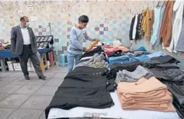  ?? VAHID SALEMI/AP ?? A street vendor adjusts clothes at his stall at the gate of a subway station in downtown Tehran, Iran. Many low-wage workers bear the brunt of Iran’s economic pain.