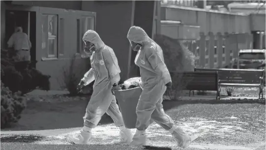  ?? TIM KROCHAK • THE CHRONICLE HERALD ?? Workers in protective gear remove a waste bin from a residence in Northwood in Halifax in this file photo. The nursing home has reported 38 deaths from COVID-19 out of a provincewi­de total of 44.