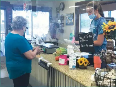  ?? Lynzie Lowe/ Appeal ?? A customer utilizes the free hand sanitizer offered at the Charter Family Fruit Stand in Williams after selecting an assortment of produce.