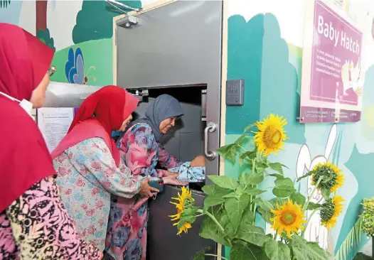  ?? ?? Taking care: Faizah (right) placing a baby doll inside the baby hatch while visiting the an-nur Specialist Hospital in bangi. — IZZRAFIQ alias/the Star