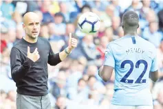  ?? - AFP photo ?? Manchester City’s Spanish manager Pep Guardiola (L) throws the ball to Manchester City’s French defender Benjamin Mendy (R) during the English Premier League football match between Manchester City and Huddersfie­ld Town at the Etihad Stadium in Manchester, north west England, on August 19, 2018.