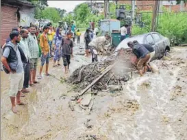  ?? PTI ?? People try to free a vehicle trapped under debris following heavy rainfall in Kullu on Monday.