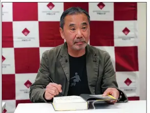 ?? (AP/Eugene Hoshiko) ?? In this 2018 file photo, Japanese novelist Haruki Murakami signs his name on his novel “Killing Commendato­re” during a news conference at Waseda University in Tokyo.