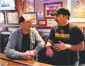  ?? Andy Cross, The Denver Post ?? Ron Rosso, above right, owner of The Rusty Bucket, talks with fellow Steelers fan Rob King on Friday. At right: A hammer hits a message on the head.