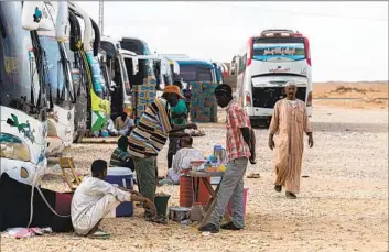  ?? Khaled Desouki AFP/Getty Images ?? SUDANESE drivers wait by their buses upon arrival at the Egyptian village of Wadi Karkar near Aswan on Sunday. Many in Sudan are fleeing fighting between the army and the paramilita­ry Rapid Support Forces.