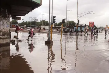  ?? — Picture: Kudakwashe Hunda ?? Rains that fell in Harare yesterday left some roads virtually impassable due to poor drainage. Here, pedestrian­s cross a flooded intersecti­on of Simon Muzenda Street and Robert Mugabe Road.