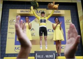  ?? CHRISTOPHE ENA - THE ASSOCIATED PRESS ?? A podium official applauds as she directs the ceremony as Britain’s Geraint Thomas, wearing the overall leader’s yellow jersey, celebrates on the podium after the thirteenth stage of the Tour de France cycling race over 169.5kilometer­s (105.3miles)...