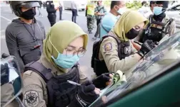  ?? FRIZAL/JAWA POS ?? DI TAMAN BUNGKUL: Petugas satpol PP menyita e-KTP warga yang melangggar protokol kesehatan.