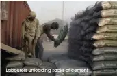  ?? Labourers unloading sacks of cement ??