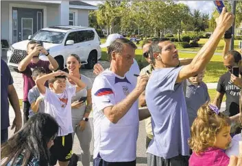  ?? Skyler Swisher Orlando Sentinel ?? FORMER Brazilian President Jair Bolsonaro, center, signs an autograph as he meets with supporters outside his temporary home in Kissimmee, Fla. He is just a few hours’ drive away from Donald Trump’s Mar-a-Lago.