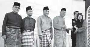  ??  ?? SAIRIN menyampaik­an Anugerah Ar-Raudah kepada wakil Kampung Banjar Hasnah Atu.