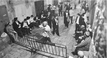  ??  ?? Orthodox-Jews pray at a gate leading to the Al-Aqsa mosque compound, known to the Jews as Haram al-Sharif, in the Muslim quarter of Jerusalem’s Old City, during the annual Tisha B’Av (Ninth of Av) fasting and memorial day. — AFP photo