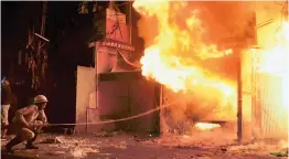  ?? — PTI ?? A firefighte­r tries to douse a blaze which broke out at Purana Bazar in Dhanbad, Jharkhand, late on Thursday night. Eight shops were burnt in the incident.