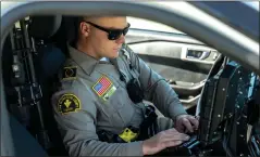  ?? ?? Strain completes a report on the missing girls in his patrol car. All but two of the Sheriff’s Department’s stations have been equipped with the body cameras since September. Officers in the Needles and Highland stations don’t have them.