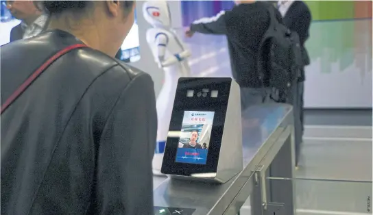  ??  ?? A China Constructi­on Bank employee demonstrat­es the use of face-scanning software.