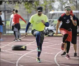  ??  ?? The Miami Marlins’ Martin Prado and New York Mets’ Jose Lobaton (right) work out pulling tires in Lake Buena Vista, Fla. , at Tom Shaw’s Performanc­e Camp.