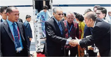  ?? — Bernama ?? Warm welcome:Dr Mahathir, accompanie­d by Basuki (in red shirt), greeting officials at the Ngurah Rai Internatio­nal Airport in Bali as Dr Siti Hasmah disembarks from the plane.