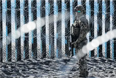  ?? PHOTO: REUTERS ?? Watchful and waiting . . . An armed US Customs and Border Patrol agent stands guards at the border fence in Tijuana.