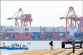  ?? AP/EUGENE HOSHIKO ?? At a seaside constructi­on site in March, workers stand near the pier of a container terminal in Tokyo. Japan reported Monday that its imports rose almost 19 percent from the same month a year earlier while exports were up 14 percent. The country’s...